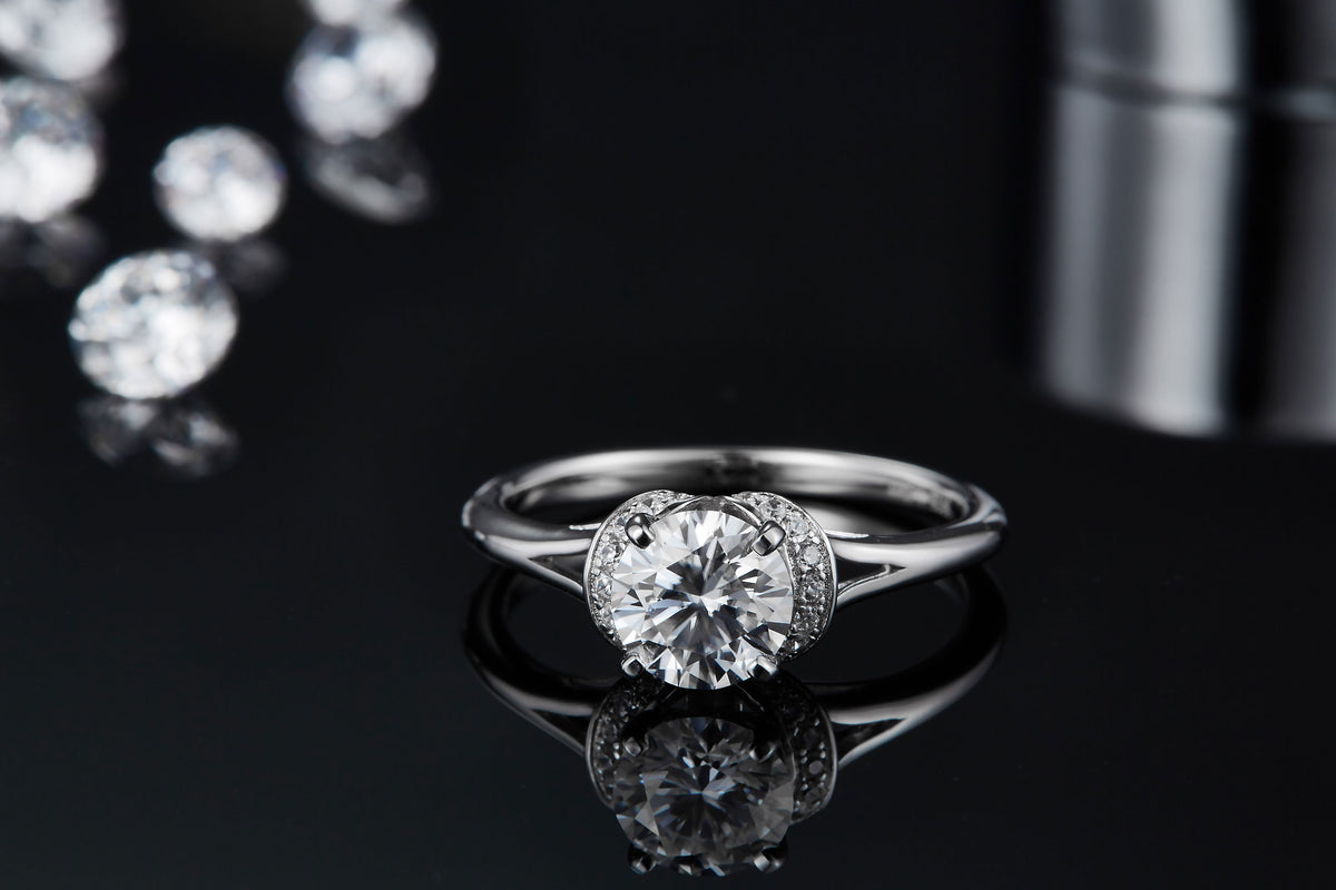 CARISSIE round moissanite solitaire ring, low angle close-up featuring clear reflection and four-prong setting detail