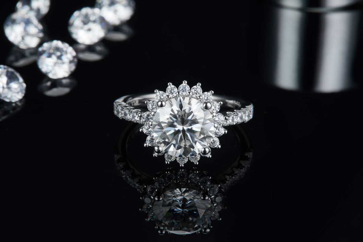 CARISSIE round moissanite halo engagement ring, front view on reflective surface emphasizing the deep sparkle of the halo