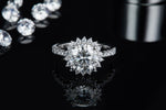 CARISSIE round moissanite halo engagement ring, front view on reflective surface emphasizing the deep sparkle of the halo