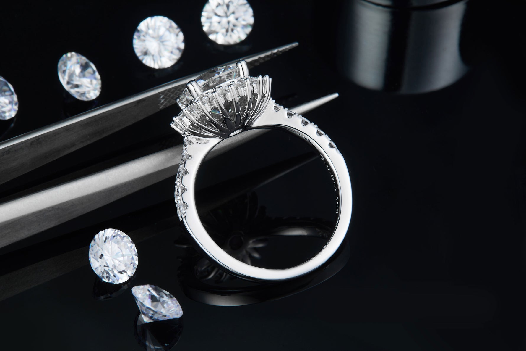 CARISSIE round moissanite halo engagement ring, side angle held by tweezers displaying the inner band stamp and metal finish