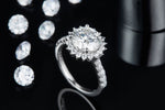 CARISSIE round moissanite halo engagement ring, lifestyle shot on black background with scattered loose stones for contrast