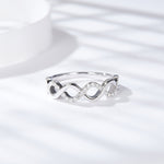 CARISSIE round moissanite pavé wedding band, angled lifestyle shot resting on a bright white surface with soft shadows.