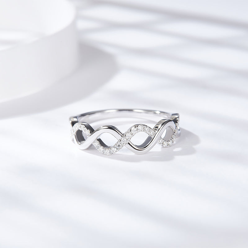 CARISSIE round moissanite pavé wedding band, angled lifestyle shot resting on a bright white surface with soft shadows.