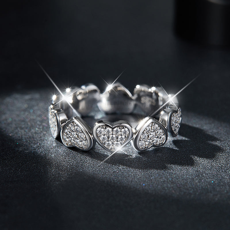 CARISSIE eternity band, dramatic close-up on dark textured background emphasizing the intense sparkle and fire of the round moissanite stones
