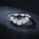 CARISSIE five-stone wedding band, close-up on dark glittery fabric showcasing the brilliance of the center round stone