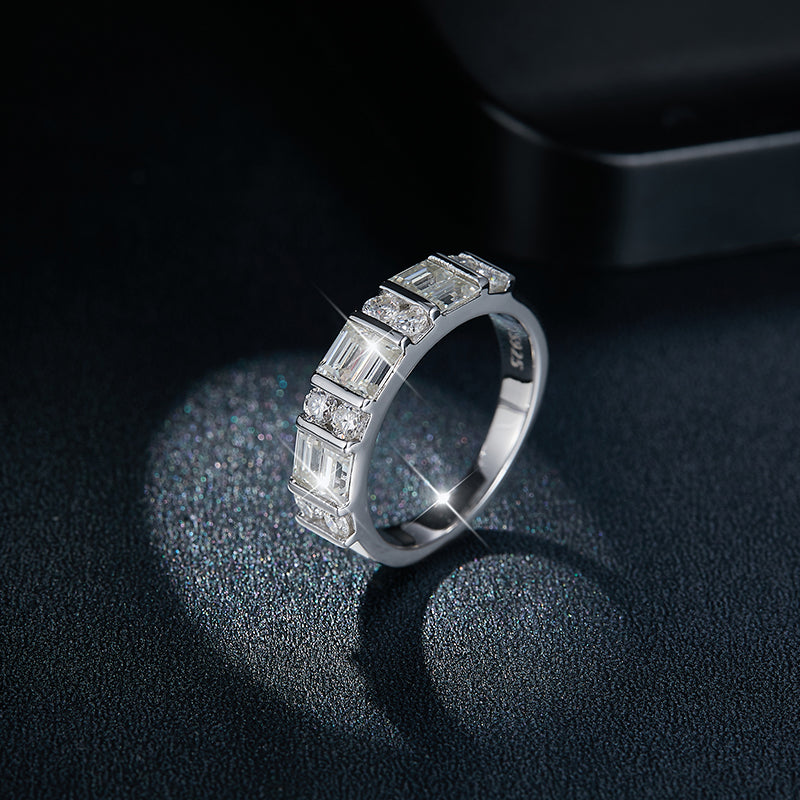 CARISSIE moissanite eternity band, lifestyle shot on dark textured surface with dramatic lighting emphasizing stone brilliance
