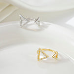 CARISSIE round moissanite pavé engagement ring, side profile of two open-shank rings placed on a smooth white ceramic plate