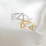CARISSIE round moissanite pavé engagement ring, angled view of yellow gold and silver-tone rings resting on soft draped cloth