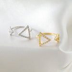 CARISSIE round moissanite pavé engagement ring, gold and silver versions displayed on white fabric with geometric triangle details