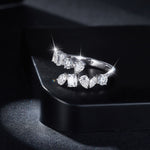 CARISSIE mixed-cut moissanite bypass ring, dramatic studio shot on black surface emphasizing high sparkle and brilliance
