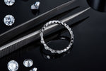 CARISSIE round moissanite eternity band, lifestyle shot on black surface with tweezers and loose gemstones nearby