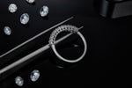 CARISSIE round moissanite eternity band, close-up held by tweezers revealing detailed craftsmanship against dark background