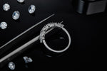 CARISSIE round moissanite eternity band, lifestyle shot on black reflective surface surrounded by loose gemstones