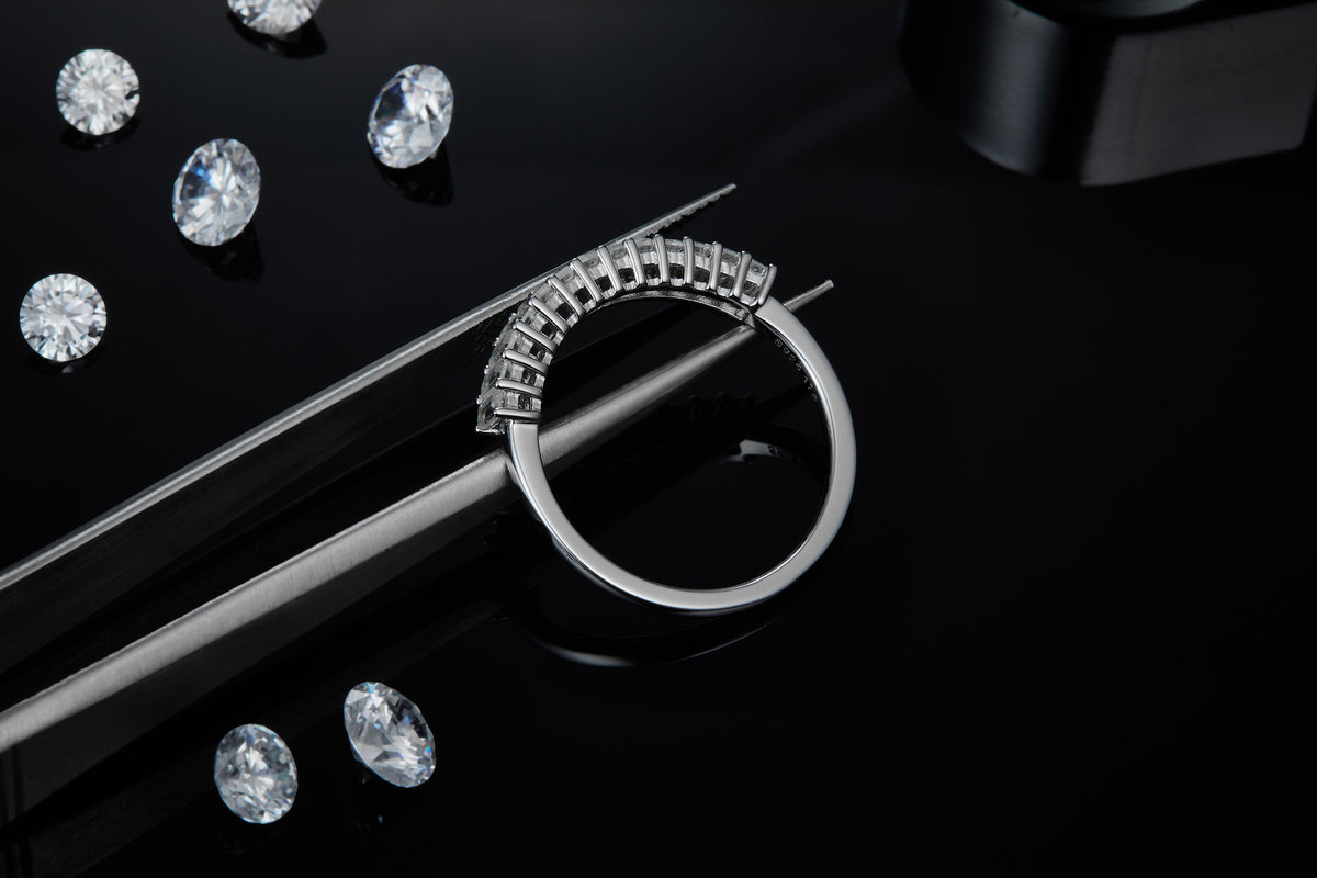 CARISSIE eternity band, held by tweezers to reveal the smooth polished interior of the silver-tone ring shank