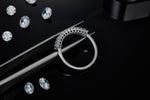 CARISSIE eternity band, held by tweezers to reveal the smooth polished interior of the silver-tone ring shank