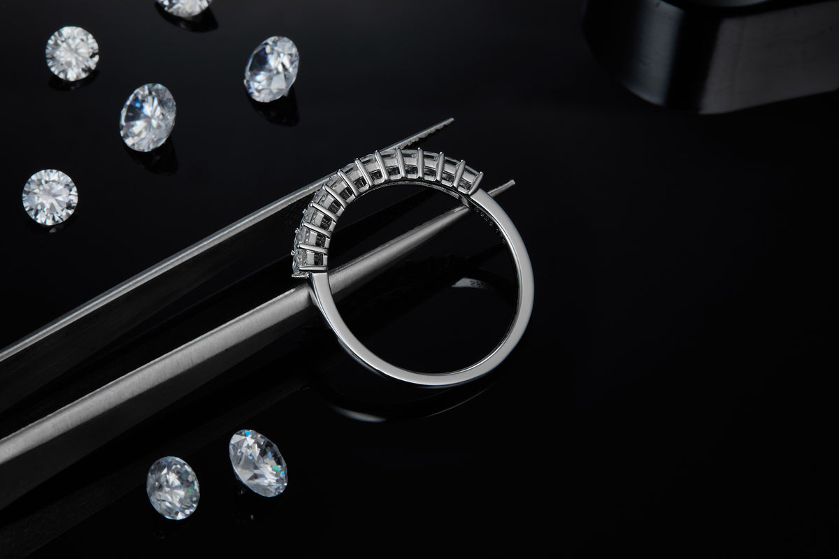 CARISSIE Princess Moissanite Eternity Band, close-up held by tweezers showing the craftsmanship of the metal band and uniform prong placement.