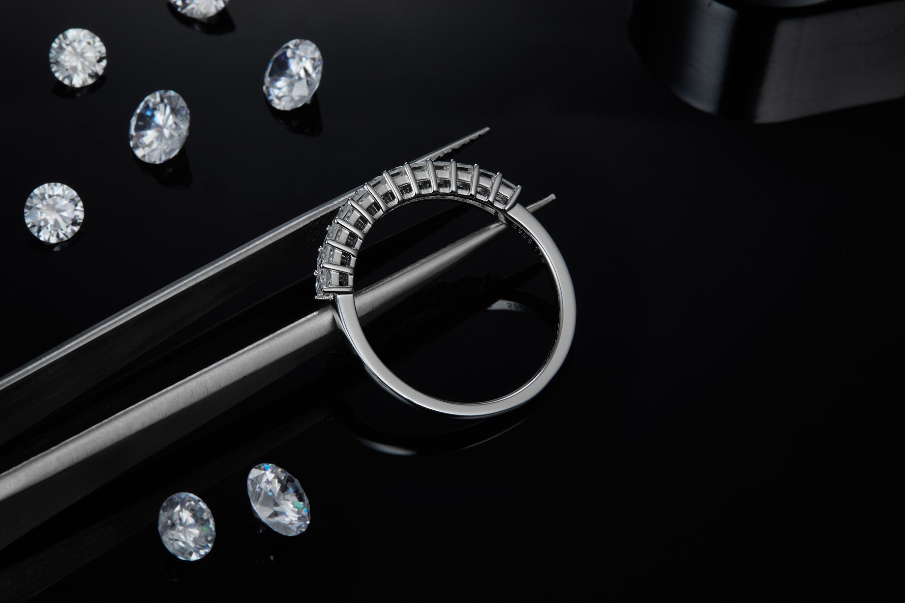 CARISSIE Princess Moissanite Eternity Band, close-up held by tweezers showing the craftsmanship of the metal band and uniform prong placement.