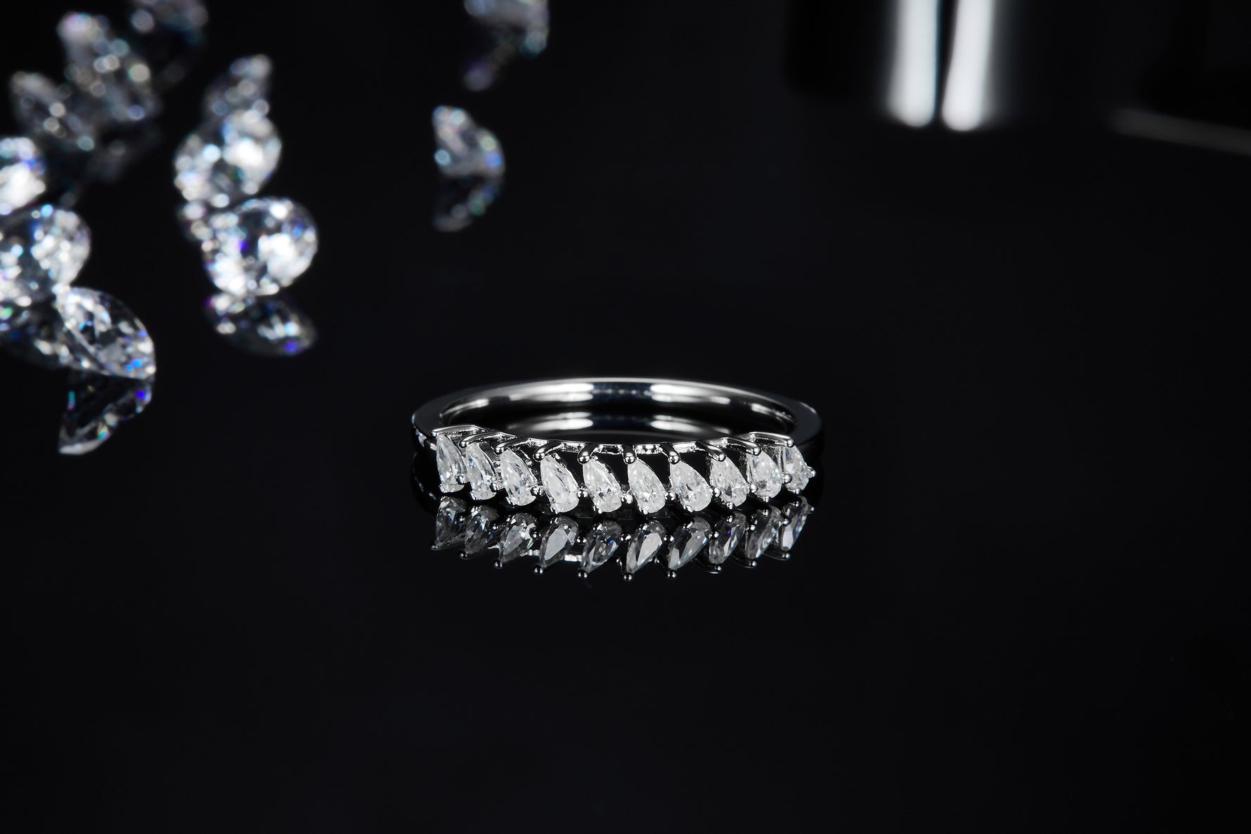 CARISSIE round moissanite solitaire ring, front-facing angle on a glossy surface showing the reflection of the row of round stones and sleek band