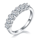 CARISSIE oval moissanite eternity band, angled view showing brilliant-cut stones in four-prong settings on a polished silver-tone metal ring