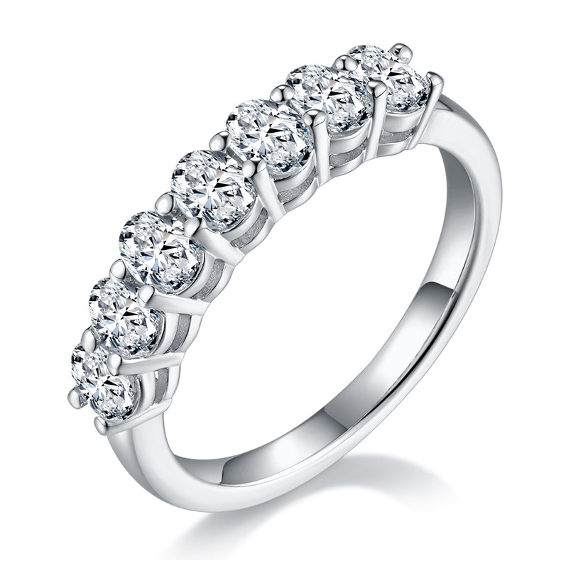 CARISSIE oval moissanite eternity band, angled view showing brilliant-cut stones in four-prong settings on a polished silver-tone metal ring
