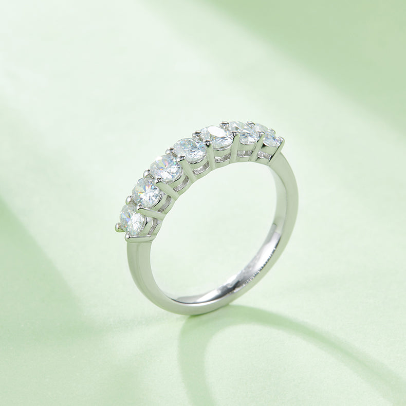 CARISSIE oval moissanite eternity band, lifestyle shot on soft green background with natural light casting gentle shadows across the sparkling stones