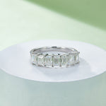 CARISSIE emerald cut moissanite ring, angled shot on white pedestal highlighting the sparkle of step-cut stones