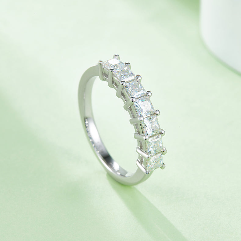 CARISSIE princess moissanite eternity band, vertical perspective on soft surface showcasing the continuous half-eternity design