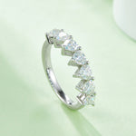 CARISSIE heart moissanite eternity band, side angle on soft green background emphasizing the sparkle and unique prong structure