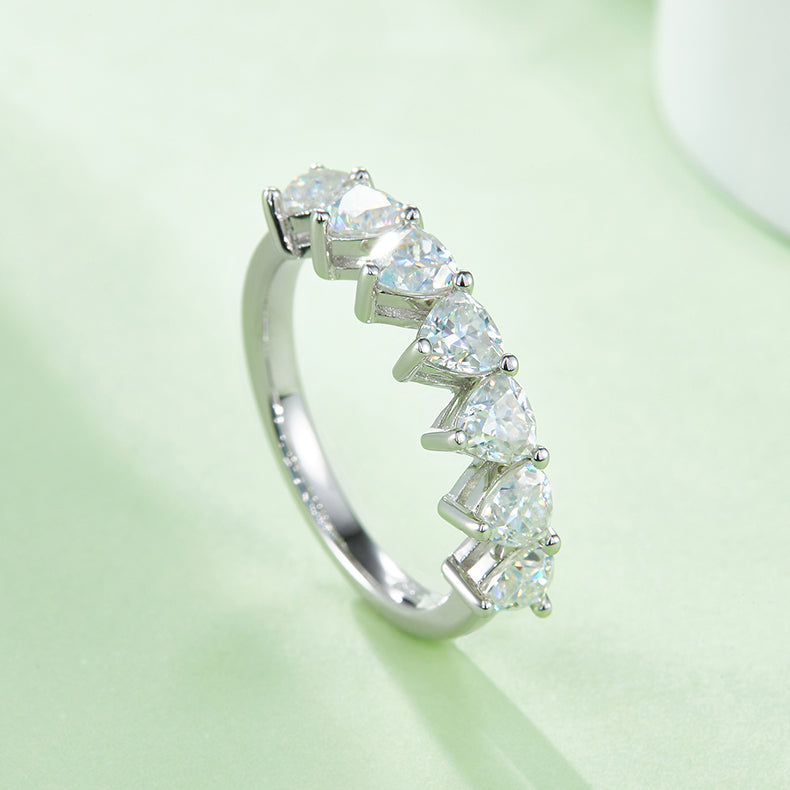 CARISSIE heart moissanite eternity band, side angle on soft green background emphasizing the sparkle and unique prong structure