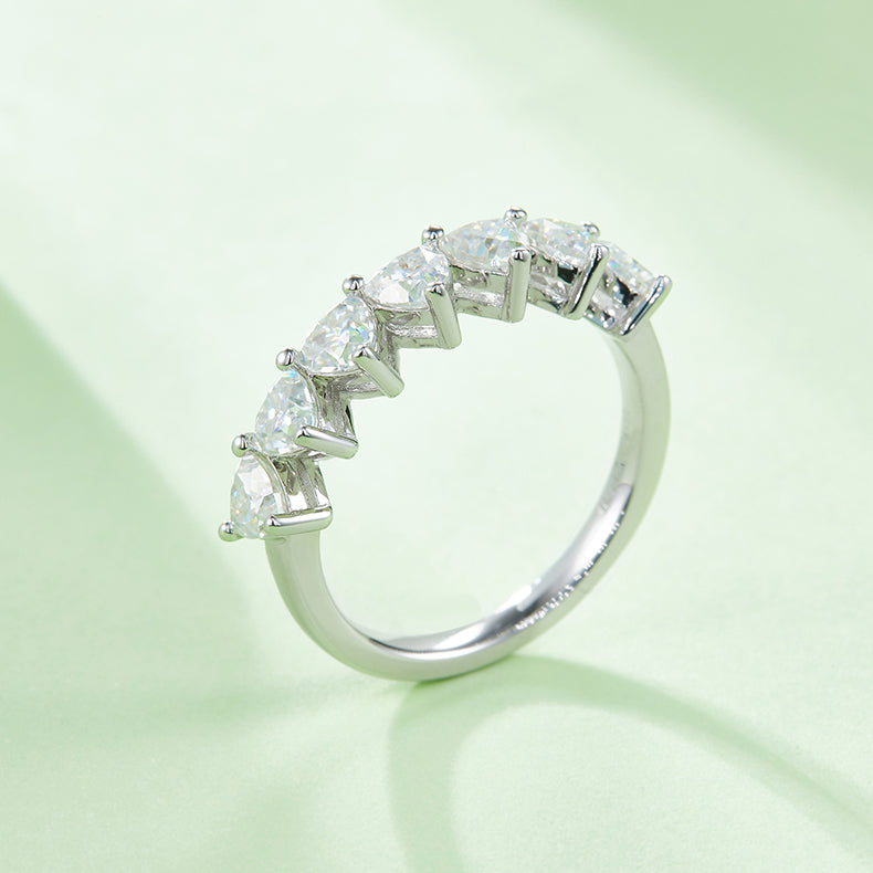 CARISSIE heart moissanite eternity band, perspective shot on green surface revealing the smooth inner band and stone arrangement