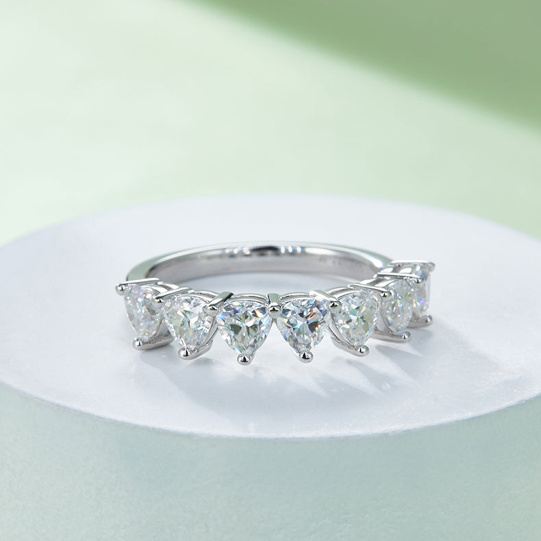 CARISSIE heart moissanite eternity band, lifestyle image on white pedestal showing the ring's elegant curve and bright finish