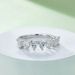 CARISSIE heart moissanite eternity band, lifestyle image on white pedestal showing the ring's elegant curve and bright finish