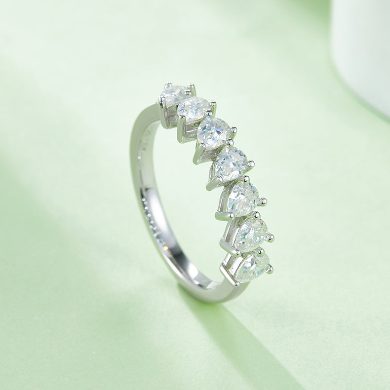 CARISSIE pear moissanite eternity band, lifestyle shot capturing the brilliant sparkle of the stones against a soft green surface