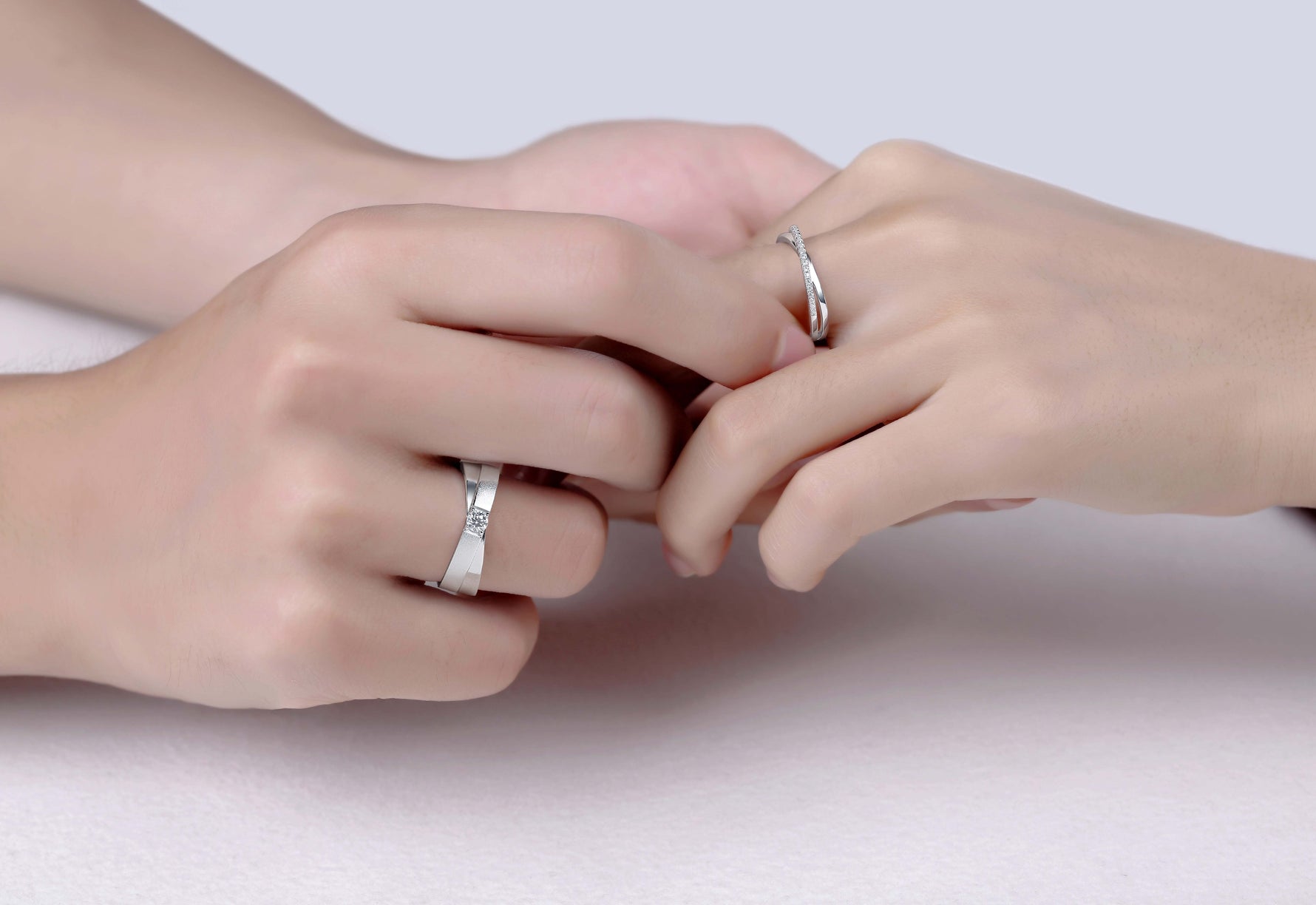 CARISSIE round moissanite pavé eternity band set, lifestyle image of couple holding hands wearing matching silver rings