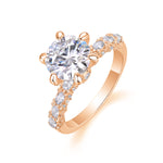 CARISSIE round moissanite solitaire ring, rose gold variant featuring warm pink tones and detailed pave diamond shoulders