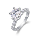 CARISSIE round moissanite solitaire ring, angled view highlighting six-prong setting and pavé marquise shoulder stones