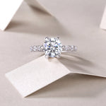 CARISSIE round moissanite solitaire ring, lifestyle shot on white paper showcasing sparkle in soft natural lighting