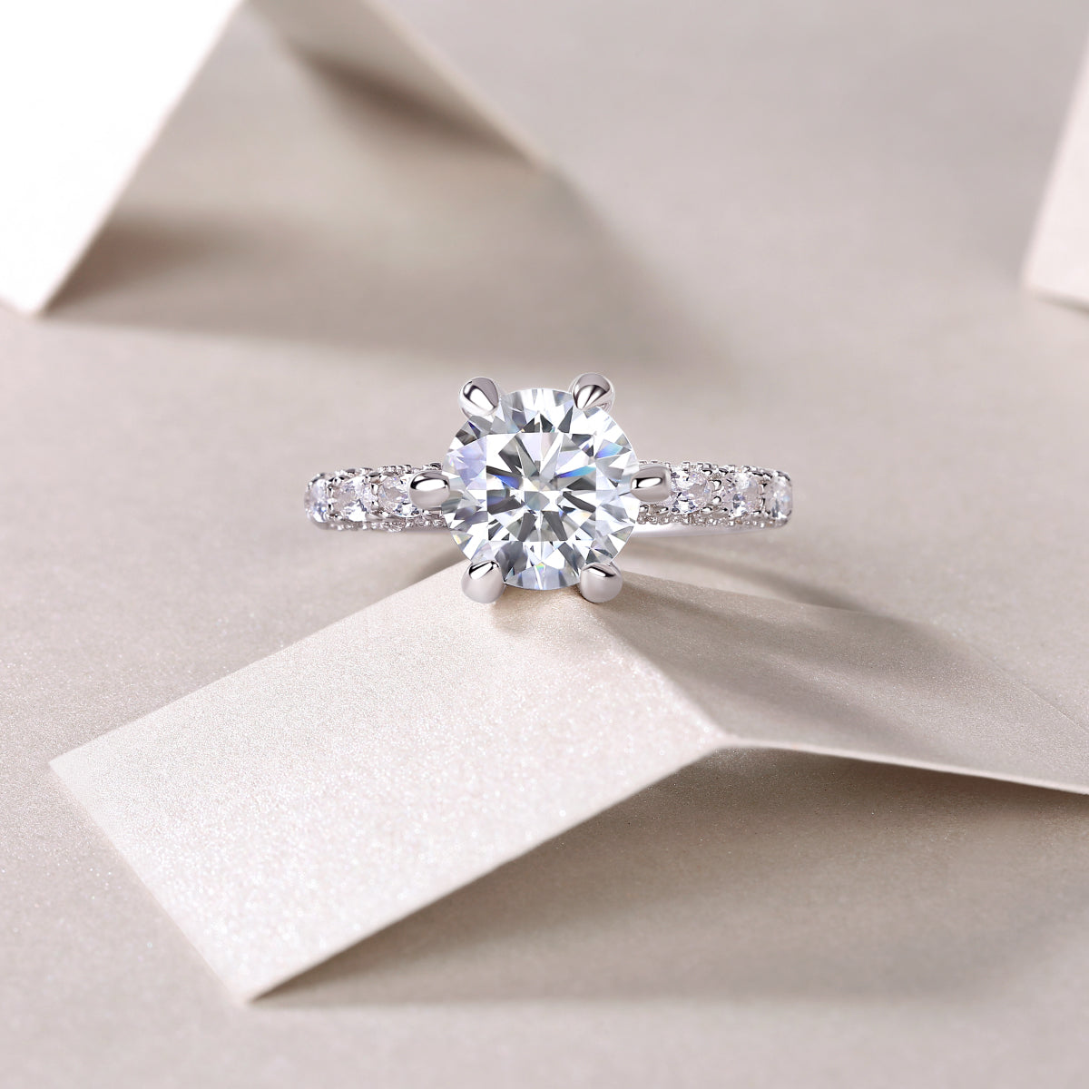 CARISSIE round moissanite solitaire ring, lifestyle shot on white paper showcasing sparkle in soft natural lighting