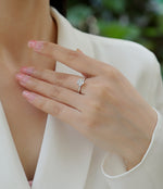 CARISSIE round moissanite solitaire engagement ring lifestyle shot on woman wearing white blouse, highlighting elegant finger placement