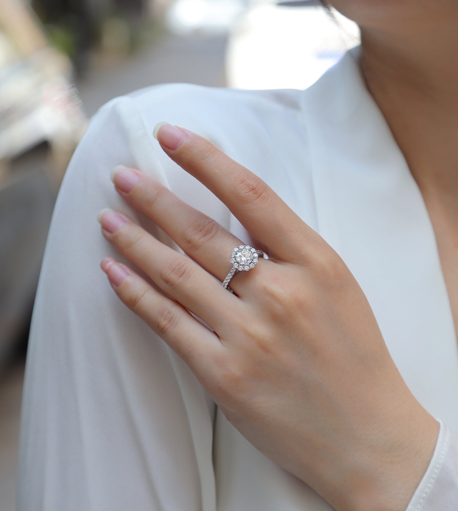 CARISSIE round moissanite halo engagement ring worn on finger, highlighting brilliance of center stone and surrounding halo