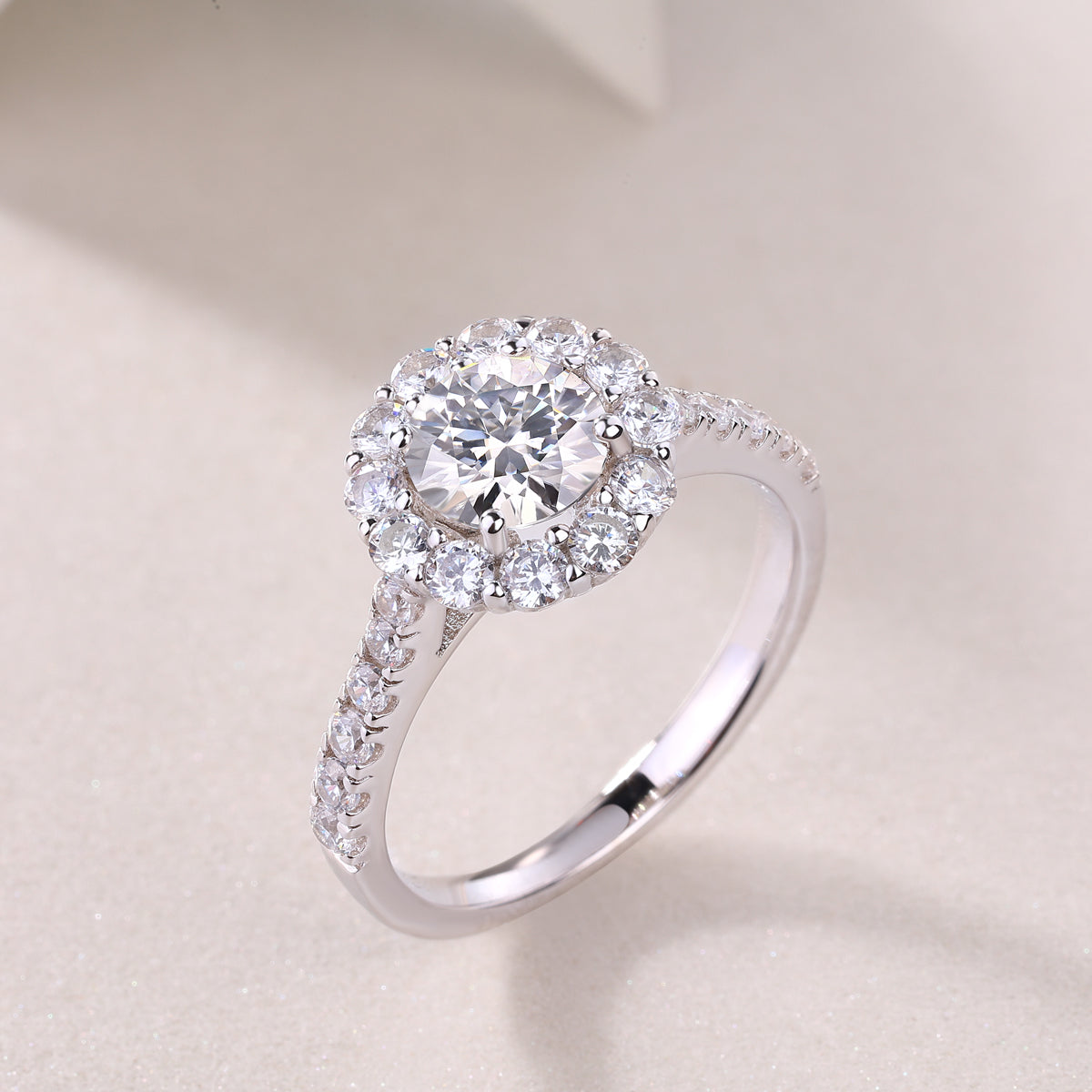 CARISSIE round moissanite halo engagement ring, three-quarter perspective capturing light reflection across the entire silver-tone band