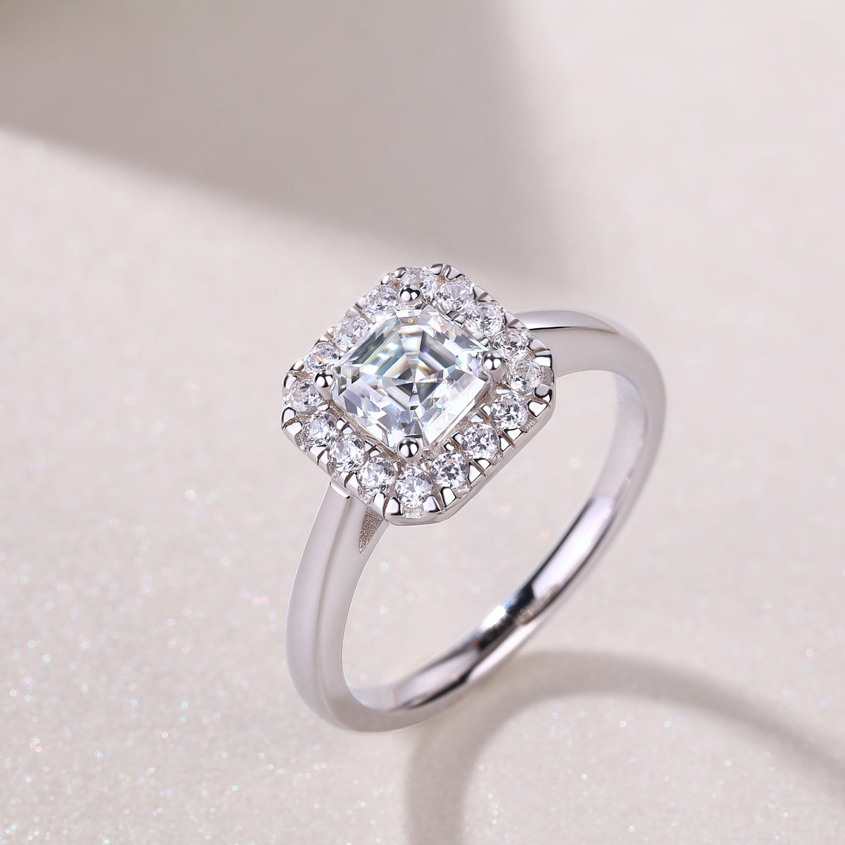 CARISSIE Asscher solitaire ring, lifestyle shot on a textured surface showcasing the sparkle of the moissanite under soft lighting