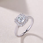CARISSIE Asscher solitaire ring, lifestyle shot on a textured surface showcasing the sparkle of the moissanite under soft lighting