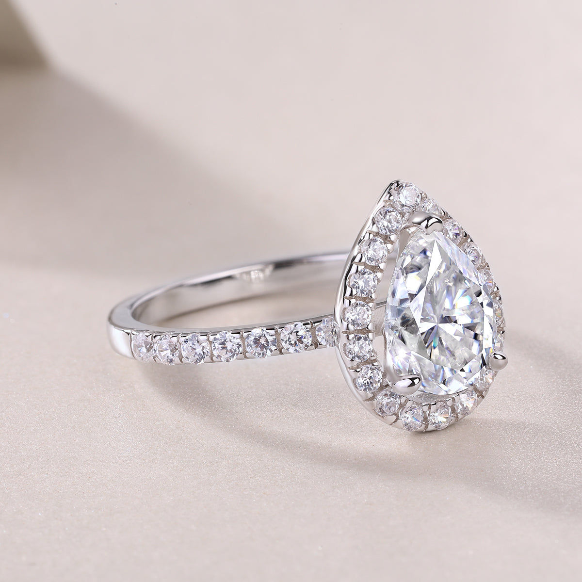 CARISSIE pear moissanite halo ring, close-up diagonal view capturing the intricate halo setting and polished finish of the metal