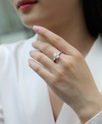 CARISSIE pear moissanite engagement ring on model, showing tapered baguette accents and pavé band against white blouse