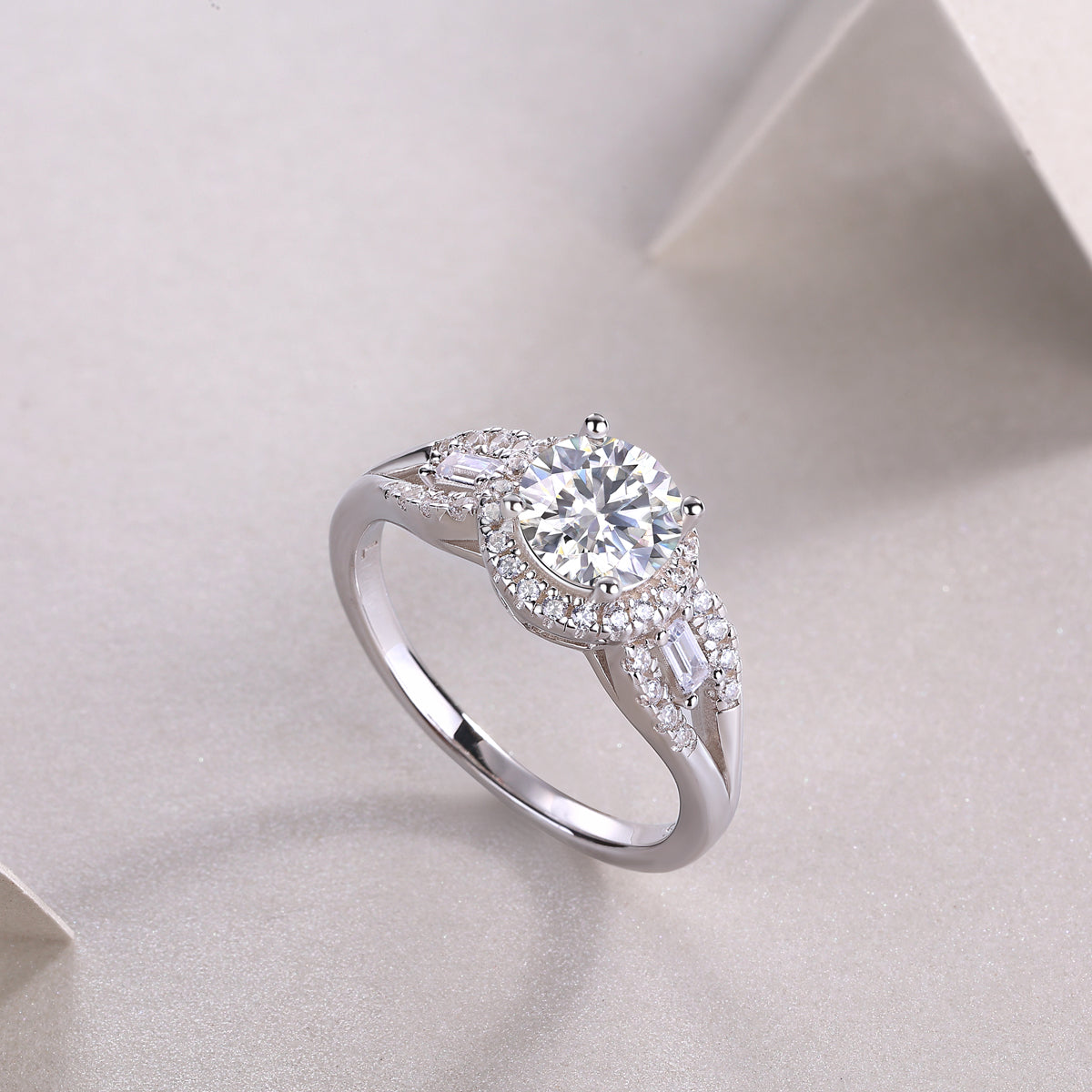 CARISSIE round moissanite halo engagement ring diagonal angle on textured surface, capturing light reflection off the round cut center stone