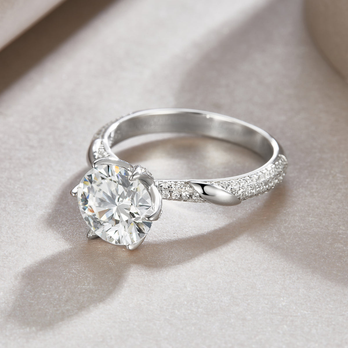 CARISSIE round moissanite solitaire ring resting on textured surface, capturing light reflection on the large center stone
