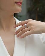 CARISSIE emerald cut moissanite halo ring on model's hand, angled view showing split shank band against white blazer