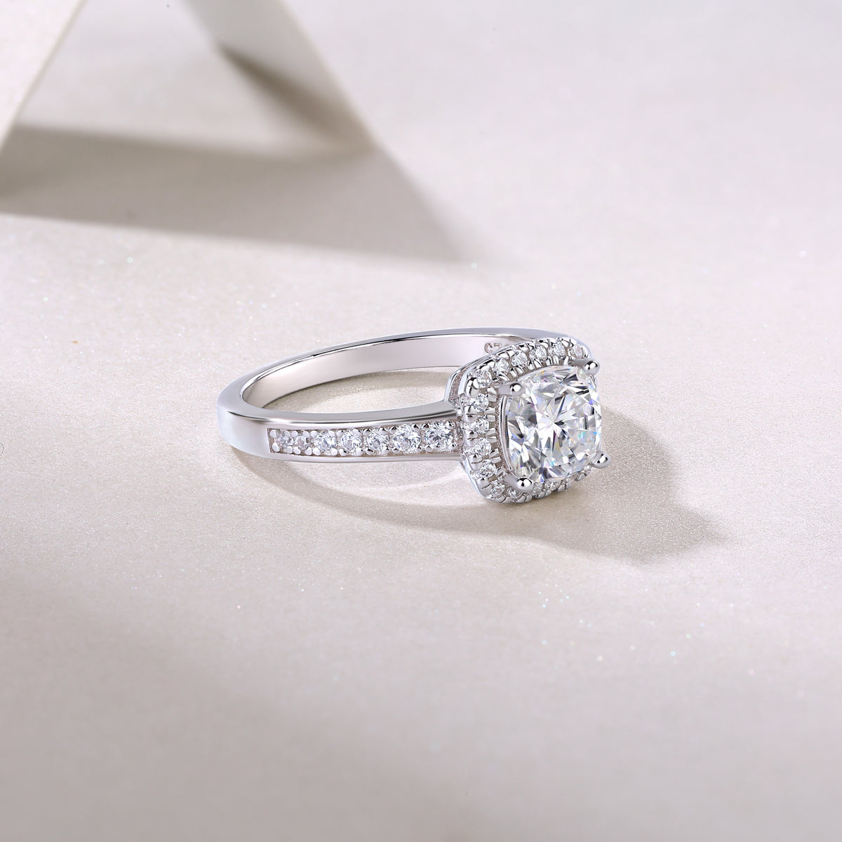 CARISSIE cushion moissanite halo ring lifestyle image, resting on textured surface to highlight the high-polish finish