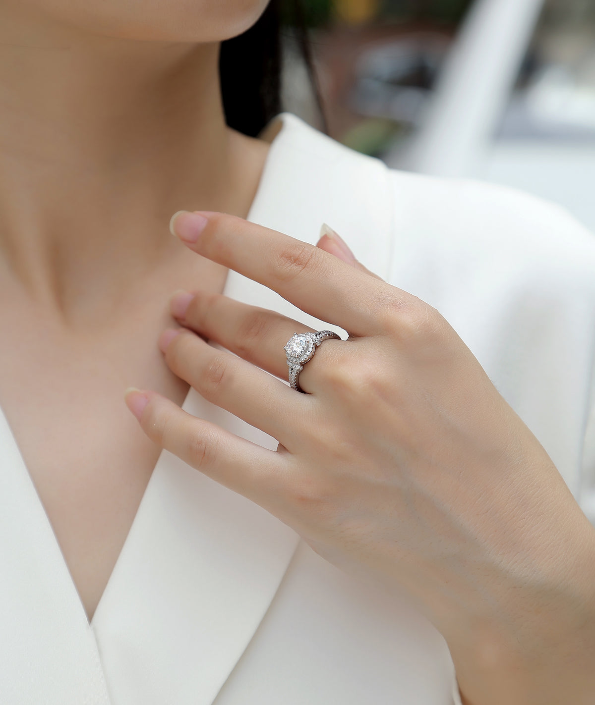 CARISSIE round moissanite engagement ring worn on finger, close-up view highlighting the sparkling halo and split shank design